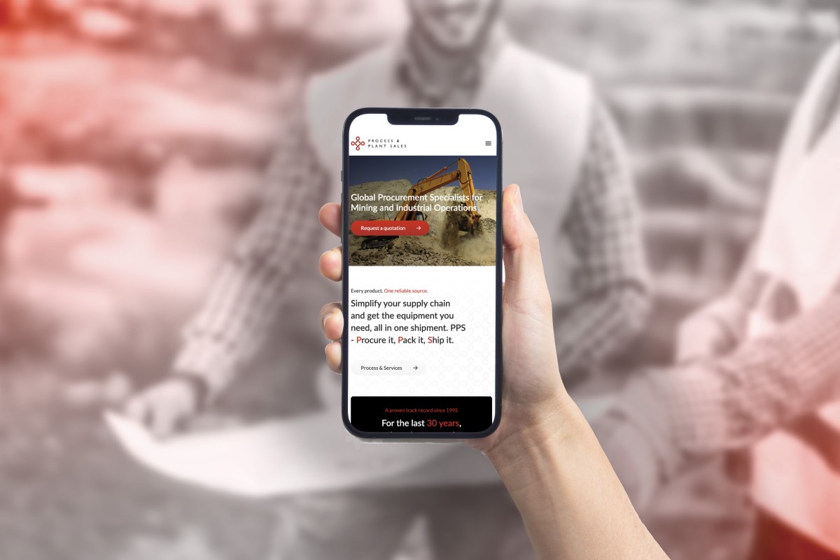 Man on mining site holds mobile phone with PPS website on display
